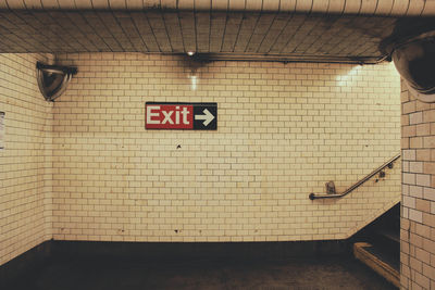 Exit sign on tile wall in subway station