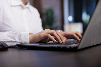 Midsection of woman using laptop on table