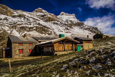 House on snowcapped mountain against sky