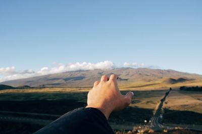 Close-up of hand against mountain