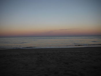 Scenic view of beach against clear sky at sunset