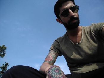 Low angle view of man wearing sunglasses against sky