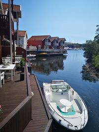 Boats moored in canal by buildings against sky