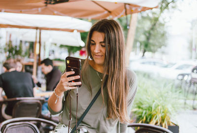 Young woman looking away while using mobile phone in bus