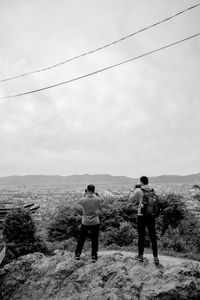 Rear view of men standing on land against sky