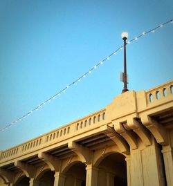 Low angle view of illuminated lights on bridge against clear blue sky