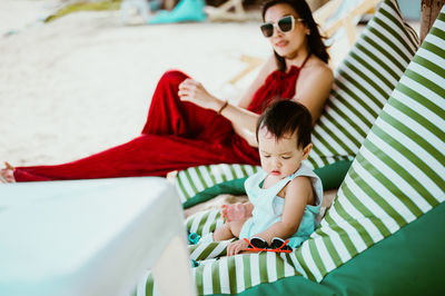 Mother and son relaxing at beach against sky