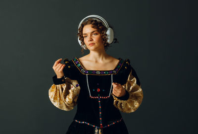 Portrait of young woman standing against black background