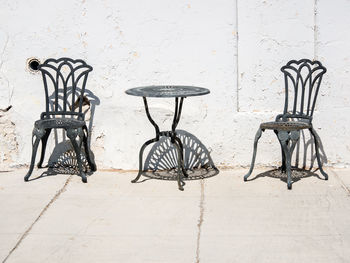 Empty chairs and table against wall