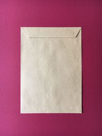 High angle view of envelop on pink background