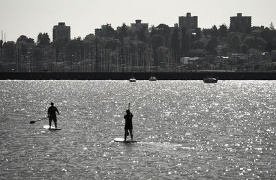 Silhouette people by sea against sky