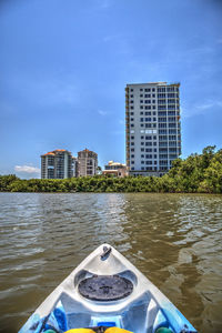 Buildings by river against blue sky