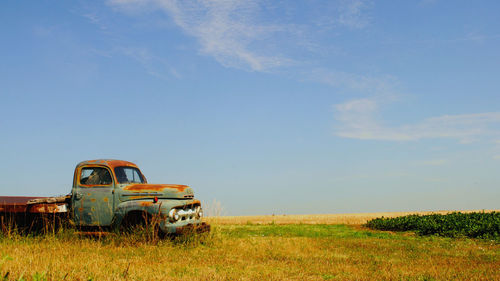 Abandoned pickup truck on field against sky