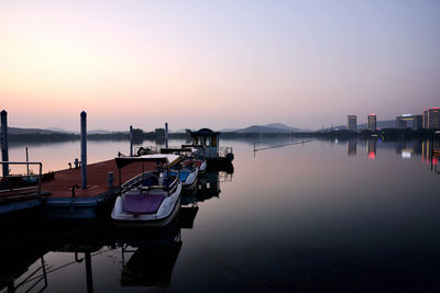 Boats moored at harbor against sky during sunset