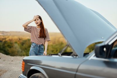 Side view of young woman holding car