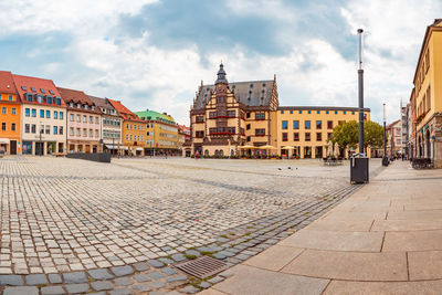 Street by buildings in town against sky