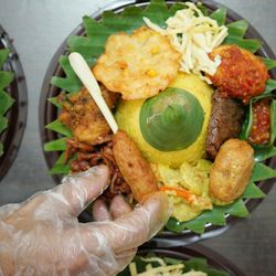 Cropped image of hand by food in plate on table