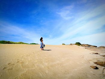 Full length of woman standing on sand at beach against sky