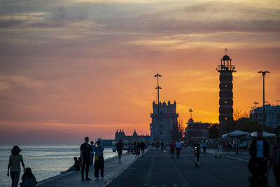 Group of people at beach against sky during sunset