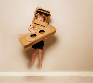 Portrait of woman holding toy blocks against wall