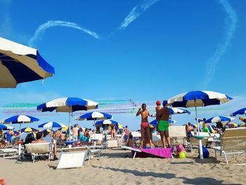 People enjoying at beach against blue sky