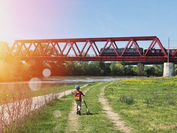 Man cycling on bridge against sky