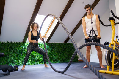 Full length of happy friends exercising in gym