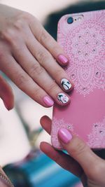 Close-up of woman with nail polishes holding smart phone