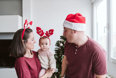 Happy family portrait with baby girl playing at home with reindeer diadem. christmas concept