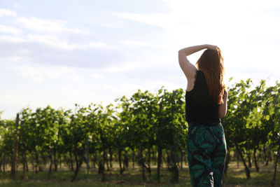 Rear view of woman standing by plants against sky