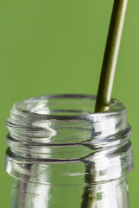 Close-up of straw in bottle against green background