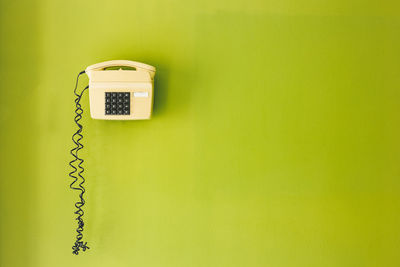 Close-up of telephone booth on green wall