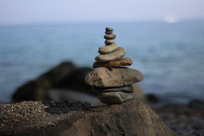 Stack of pebbles by sea against sky