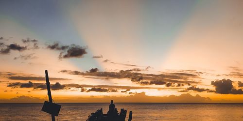 Silhouette people on beach against sky during sunset