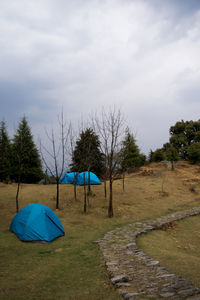 Tent and trees on field against sky