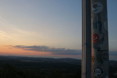 Close-up of sign board against sky during sunset