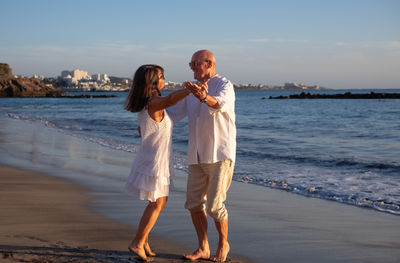 Full length of woman standing at beach against sky