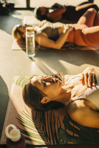 Woman with hand on chest lying by friends during yoga class at retreat center