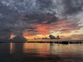 Scenic view of sea against dramatic sky during sunset