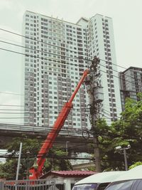 Low angle view of cherry picker against skyscraper