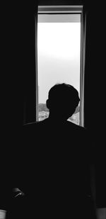 Silhouette man standing by window at home