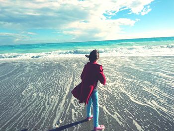 Rear view of man on beach against sky