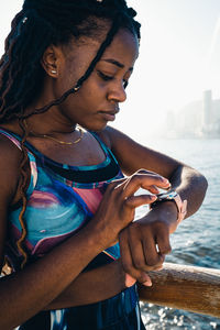 Crop african american female wearing sportswear checking health indicators on tracker after outdoor workout in sunny day