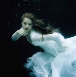 Digital composite image of teenage girl in white dress swimming underwater