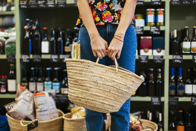 Mid section of customer holding basket in a store