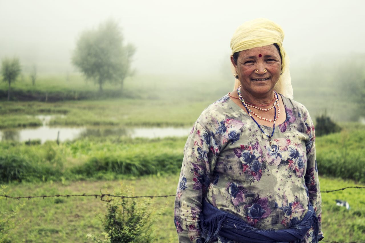 leisure activity, lifestyles, standing, focus on foreground, smiling, front view, person, weather, warm clothing, three quarter length, looking at camera, fog, casual clothing, field, nature, day, beauty in nature, foggy