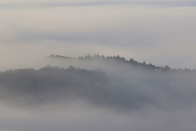 Scenic view of fog covered mountain against sky