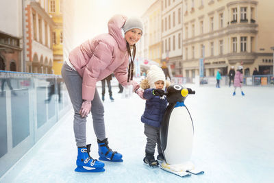 Full length portrait of happy friends standing on snow during winter