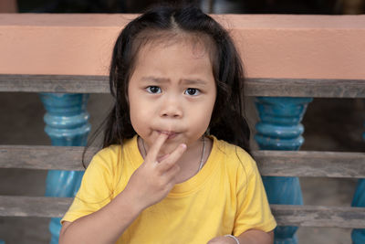 Portrait of adorable child asian woman, cute little girl with beautiful eyes sucking fingers 
