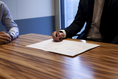 Midsection of man reading book on table